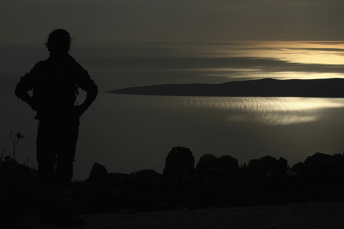A silhouetted woman looking at a view of the Adriatic Sea near Unije, Croatia