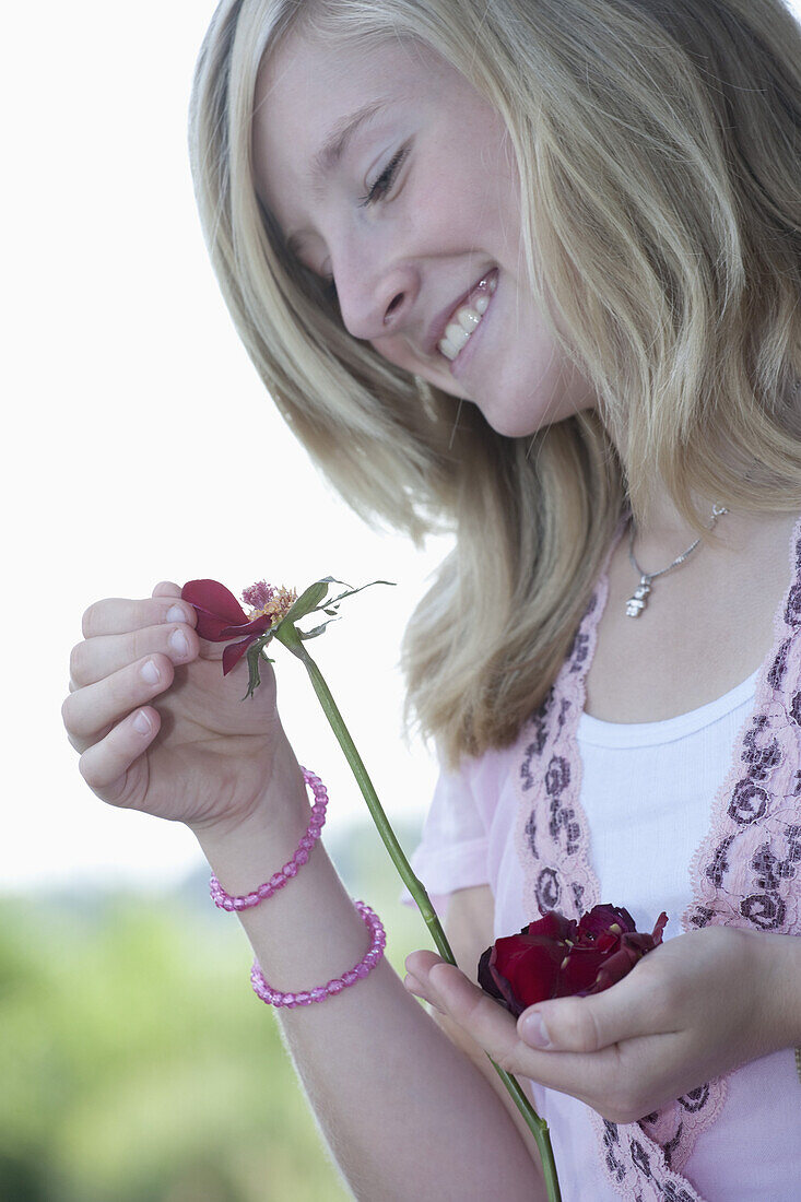 A teenage girl picking petals from a flower