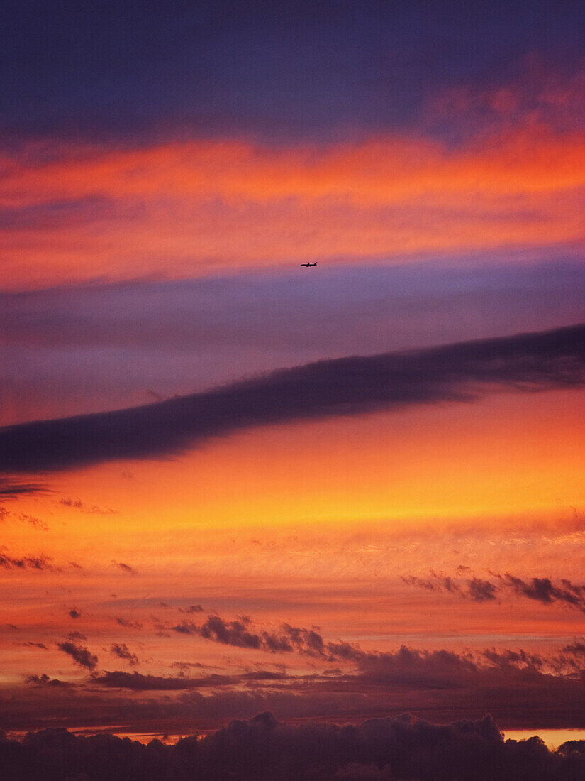 An airplane flying in the sky as the sun sets