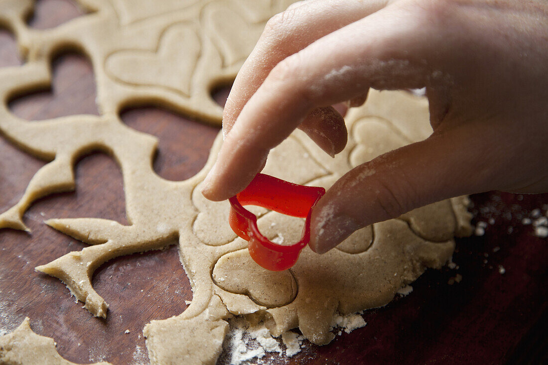 Detail of a hand using a heart shape cookie cutter