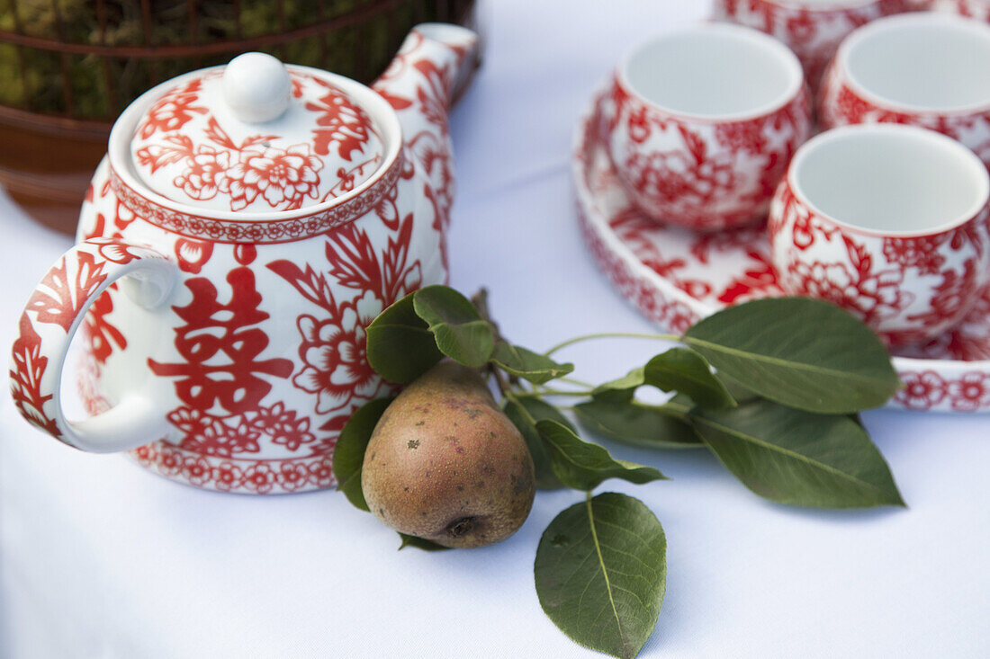 A ceramic tea set and a pear on a table
