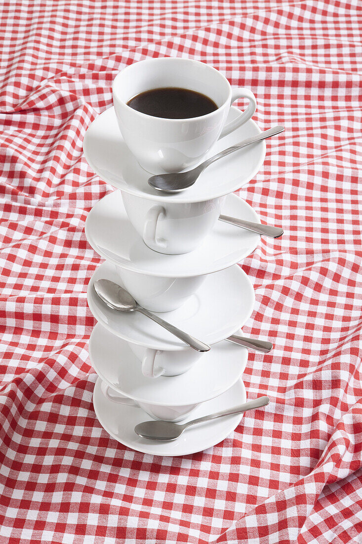 Stack of coffee cups and saucers with coffee in them