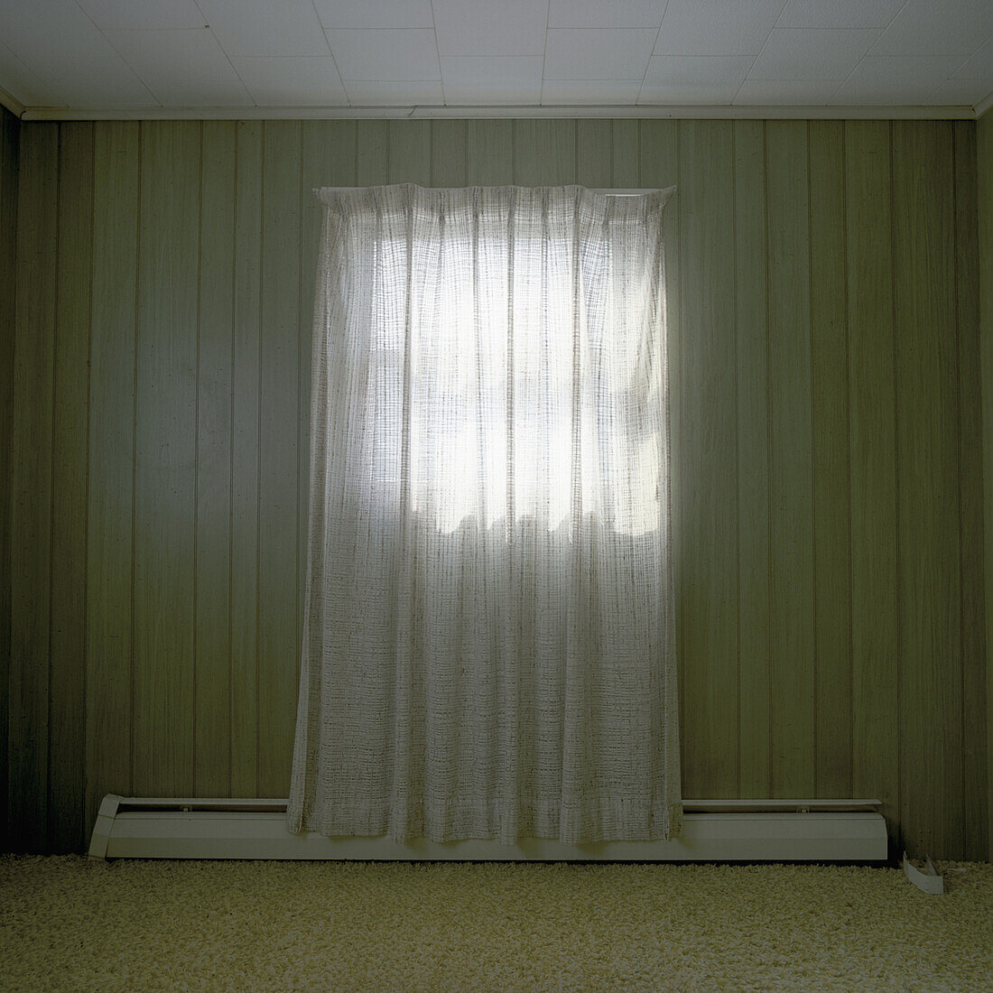 A room bare of furniture with a single curtained window