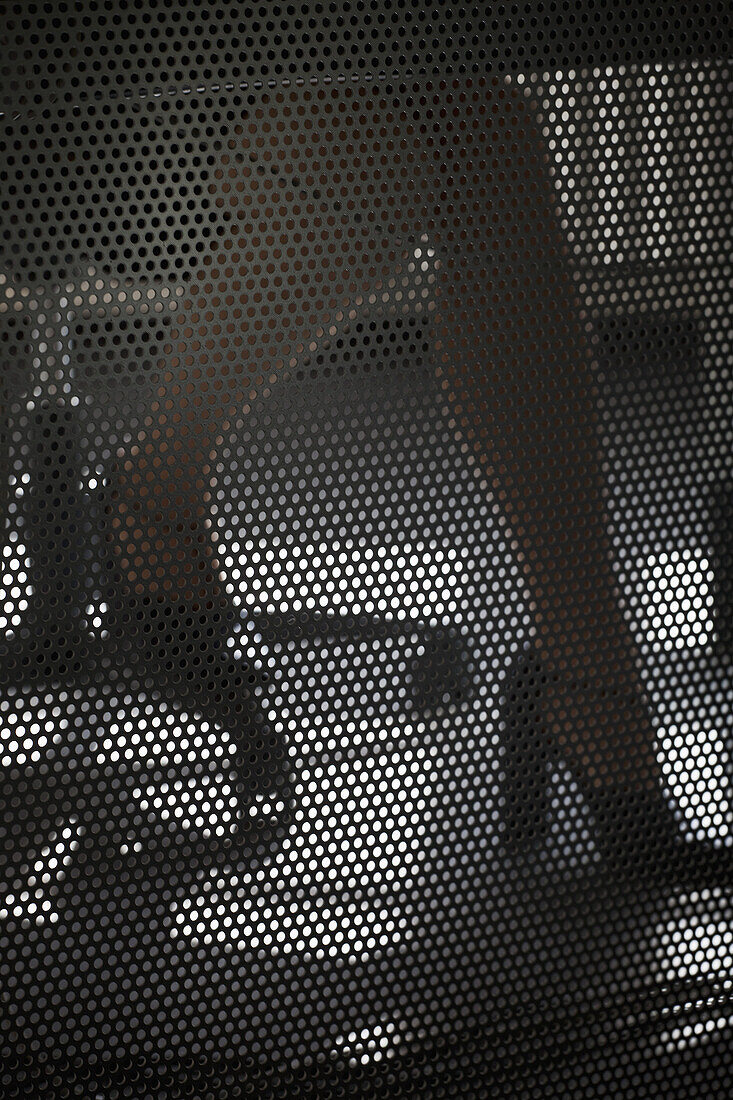 A businesswoman working at a desk, close-up of legs behind wire mesh screen