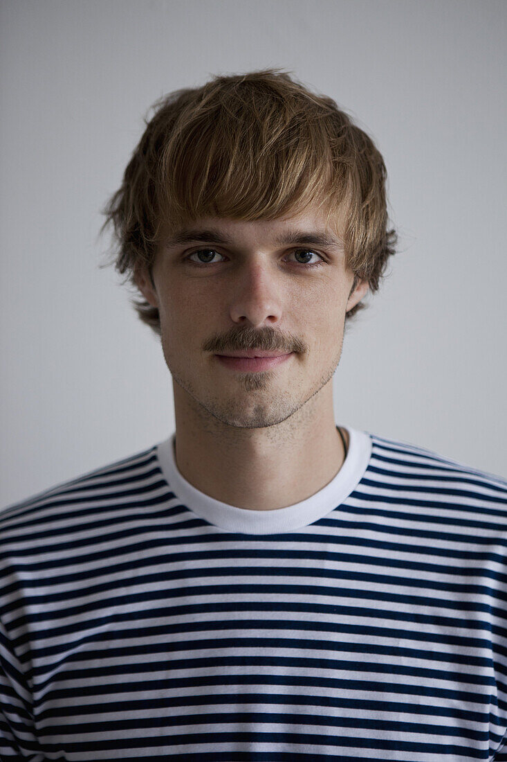 A hip young man wearing a striped t-shirt, looking at camera