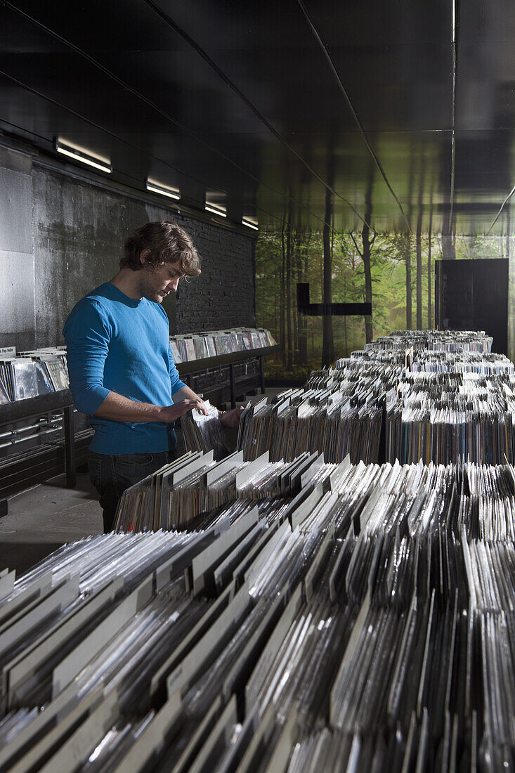 A young man searching through records in a record store