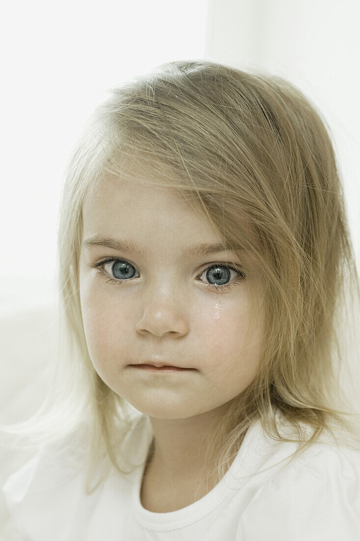 A young girl with a tear falling down her cheek