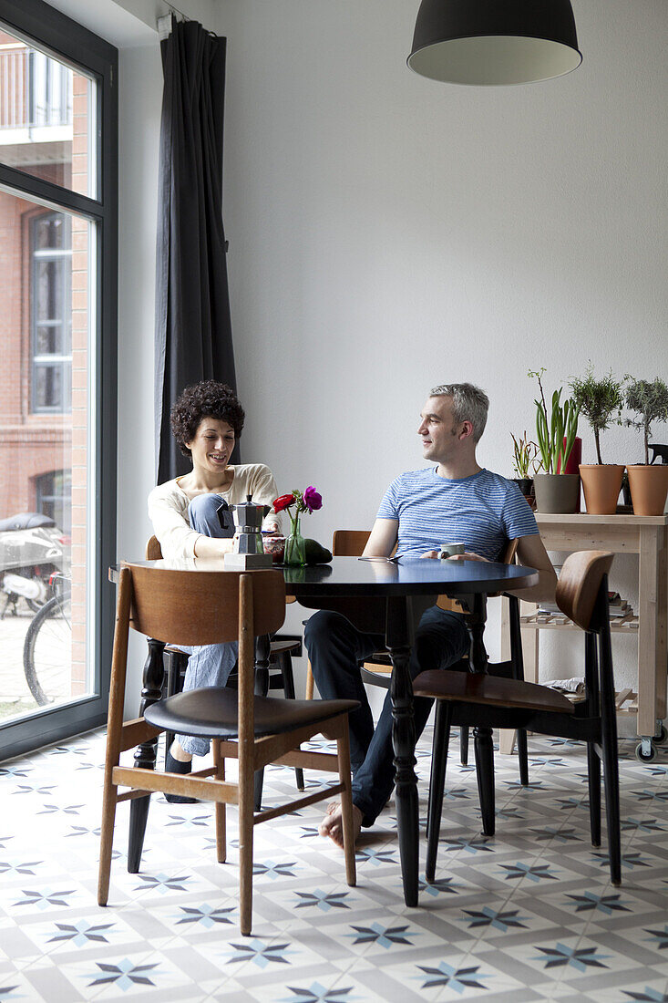 A cheerful hip mixed age couple enjoying breakfast together in their dining room