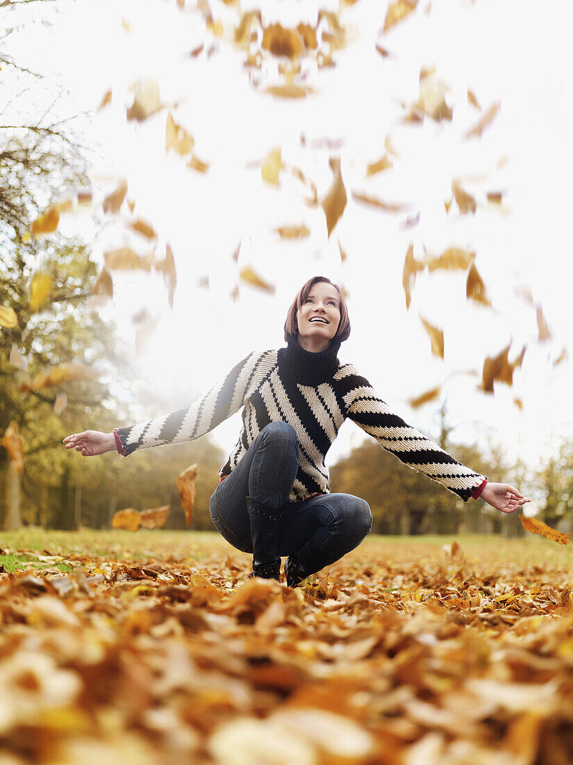 A woman looking up as autumn leaves fall
