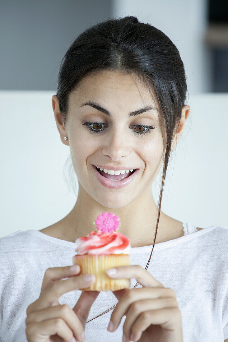 Frau freut sich über einen Blumenkopf-Cupcake