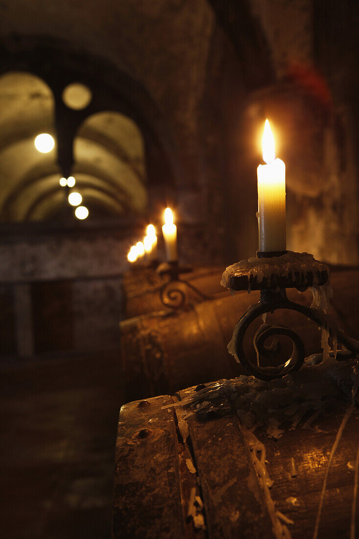 Barrels of wine in cellar lit by candlelight