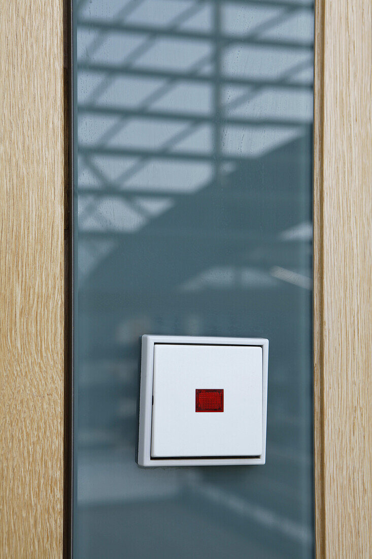 German light switch against glass reflecting a staircase
