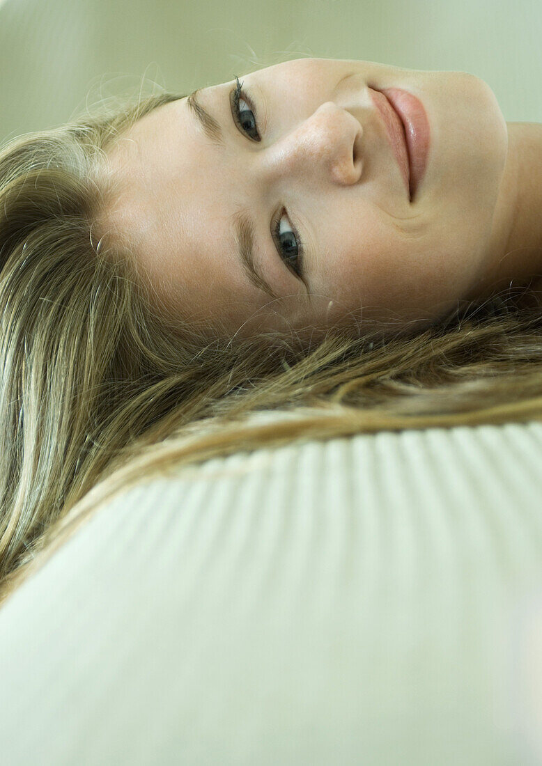 Young woman reclining, smiling at camera, close-up of face