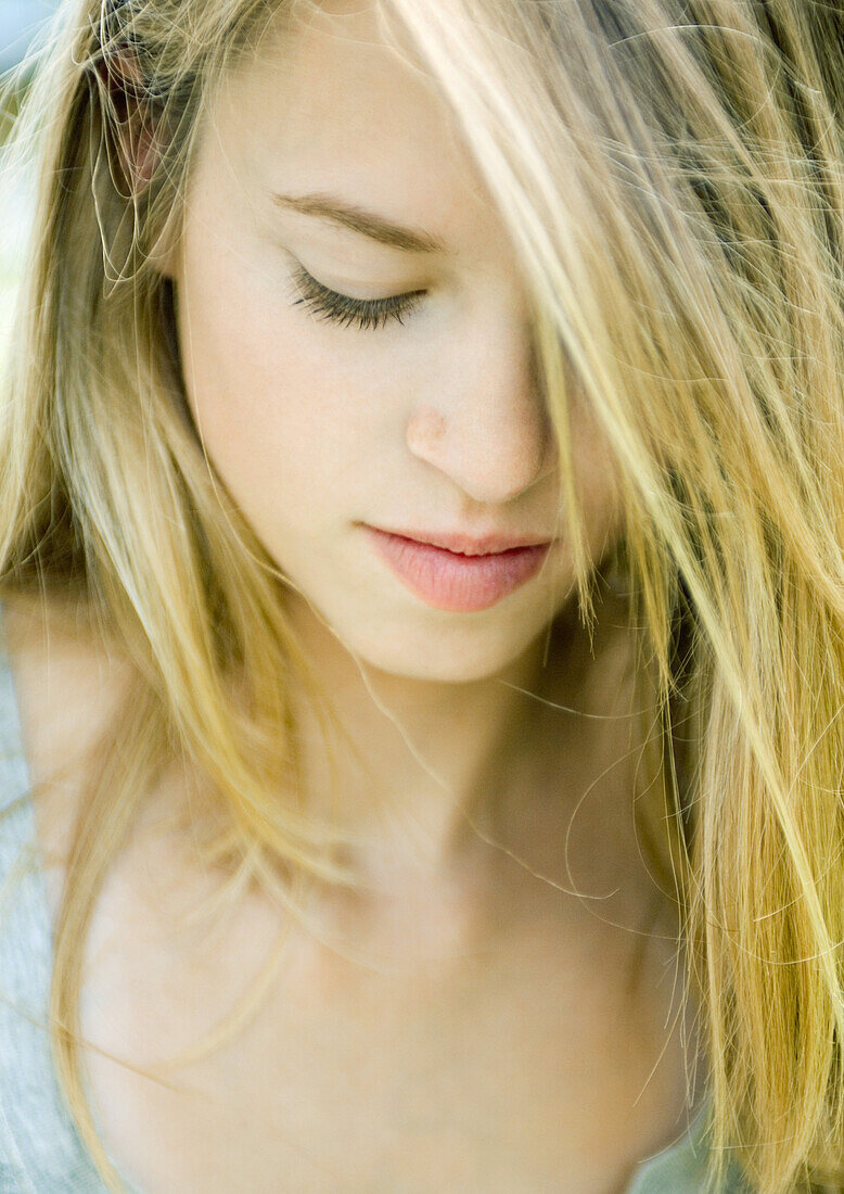 Young woman looking down, hair covering one eye, portrait