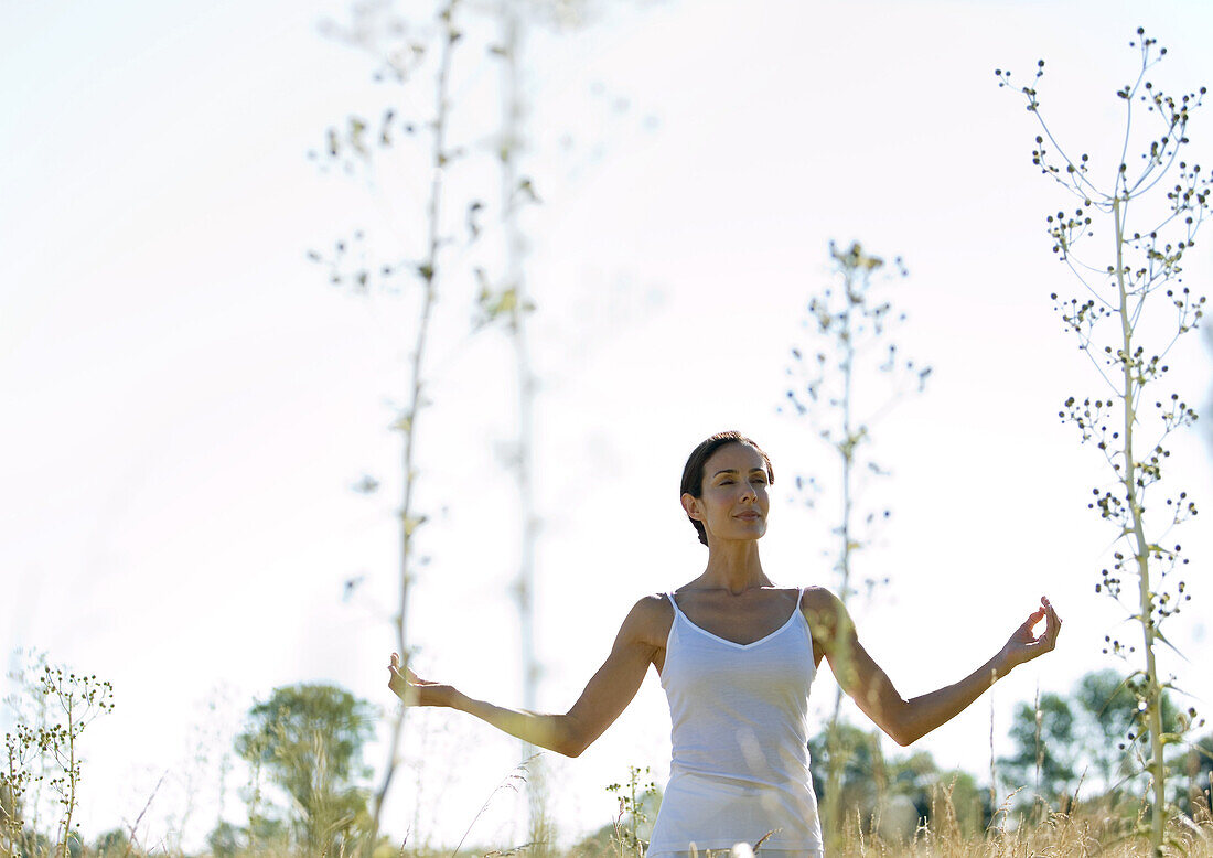 Woman doing yoga pose in field