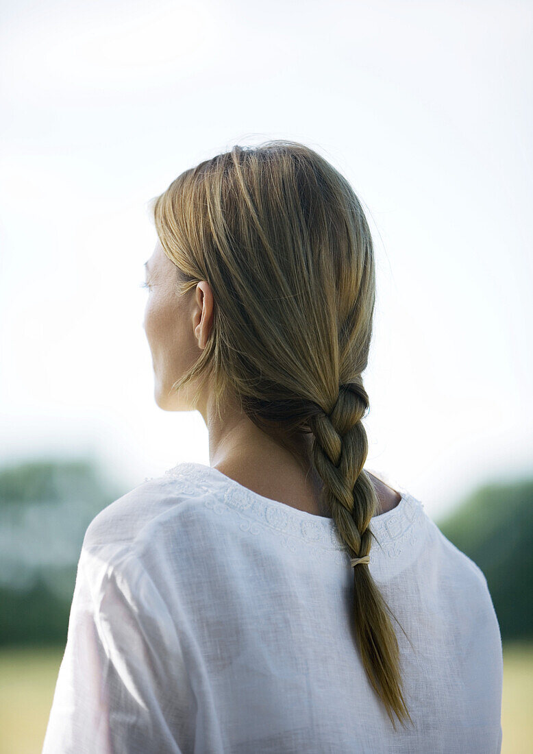 Woman outdoors, hair braided, rear view