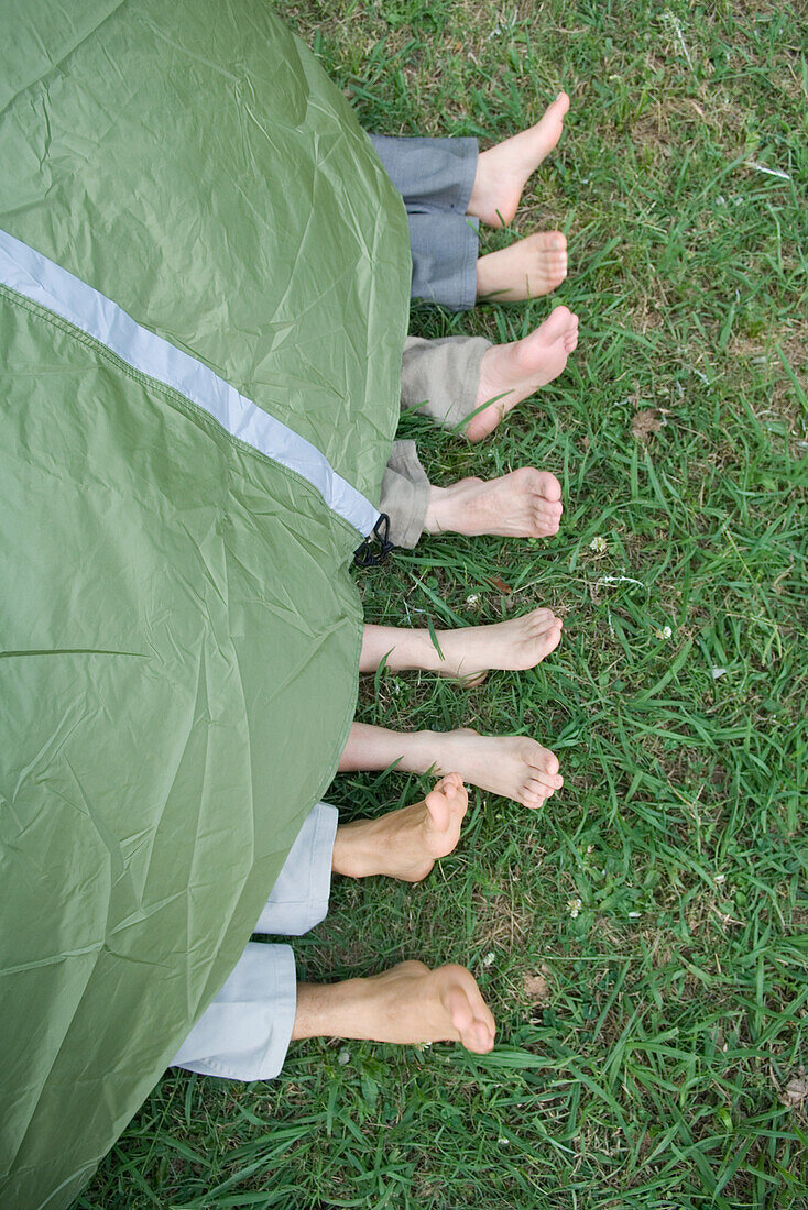 Young friends in tent, feet sticking out, high angle view