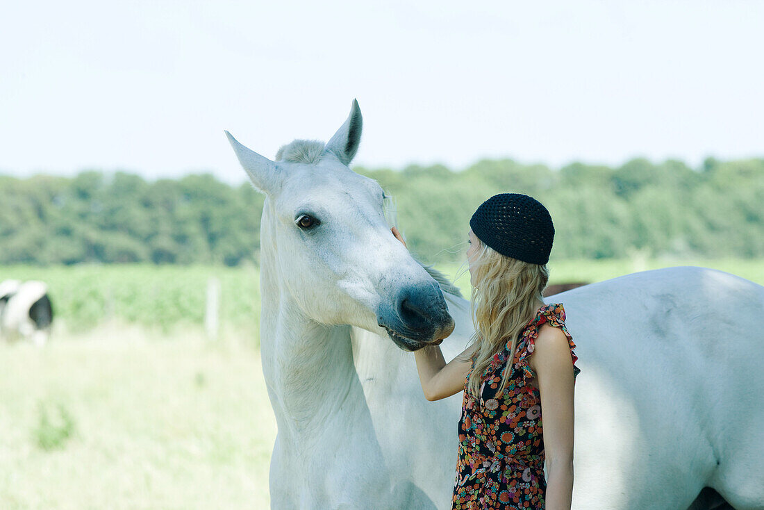 Young woman touching horse