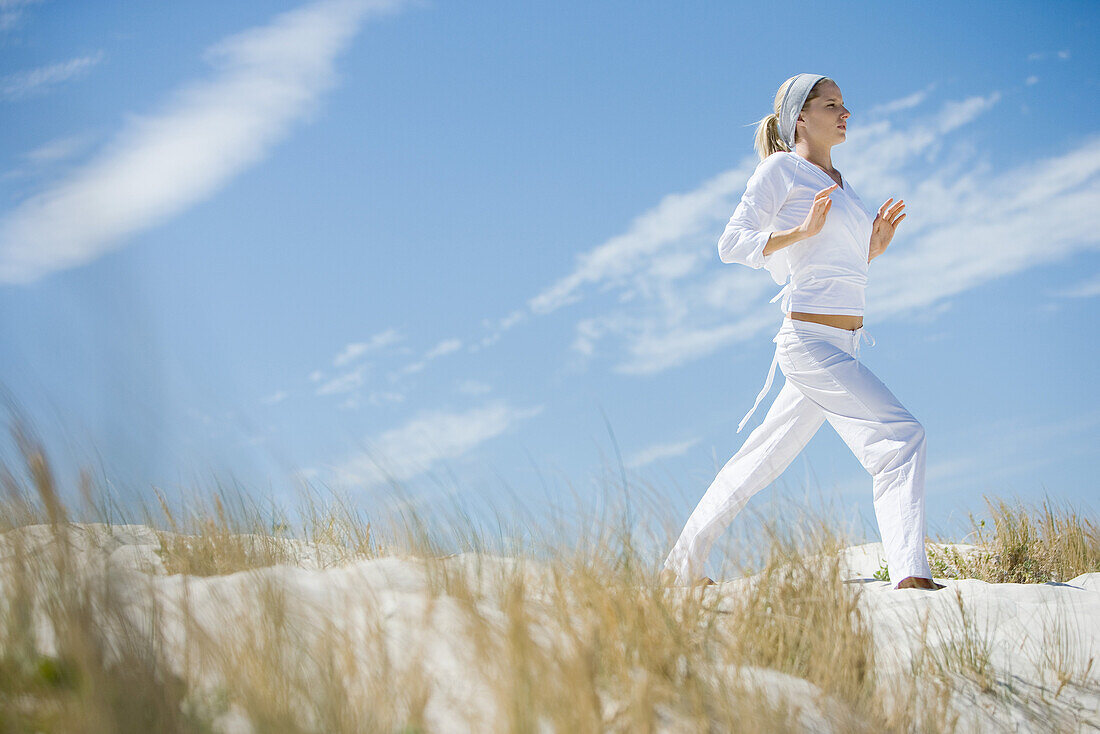 Junge Frau auf einer Düne stehend, sportlich