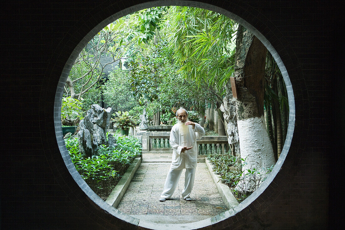 Elderly man wearing traditional Chinese clothing doing Tai Chi