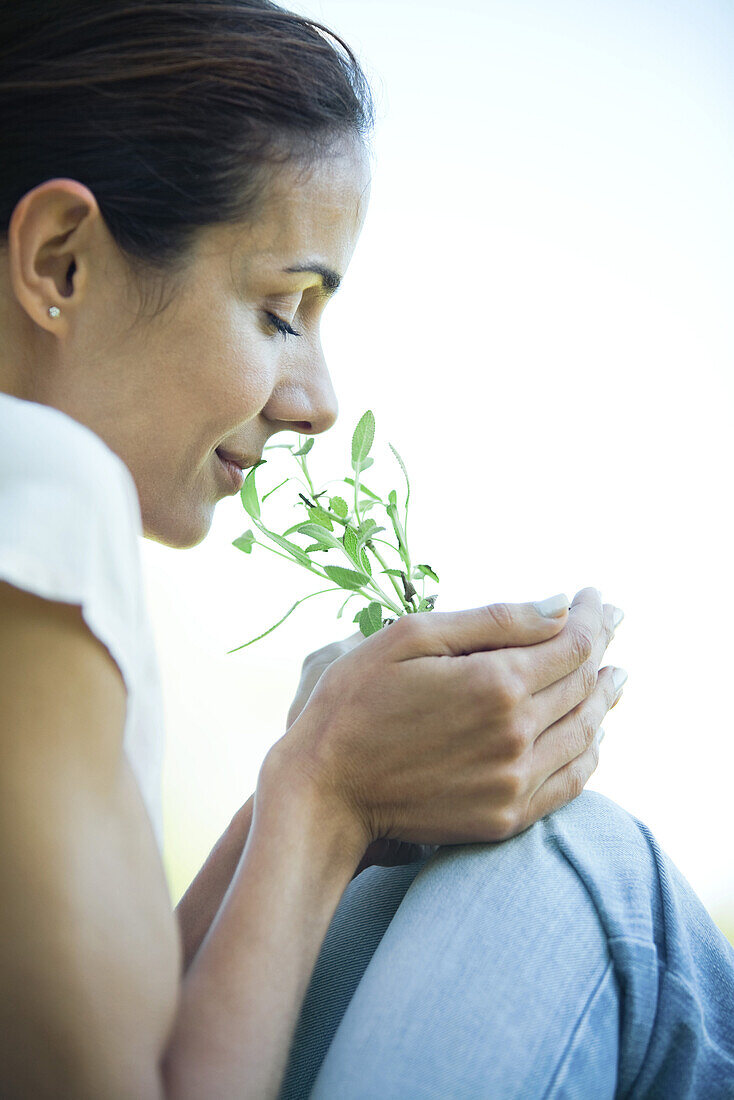 Woman smelling herbs, cropped view