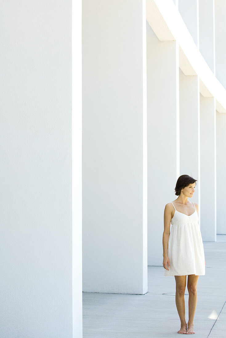 Woman in sundress standing outdoors in front of modern colonnade
