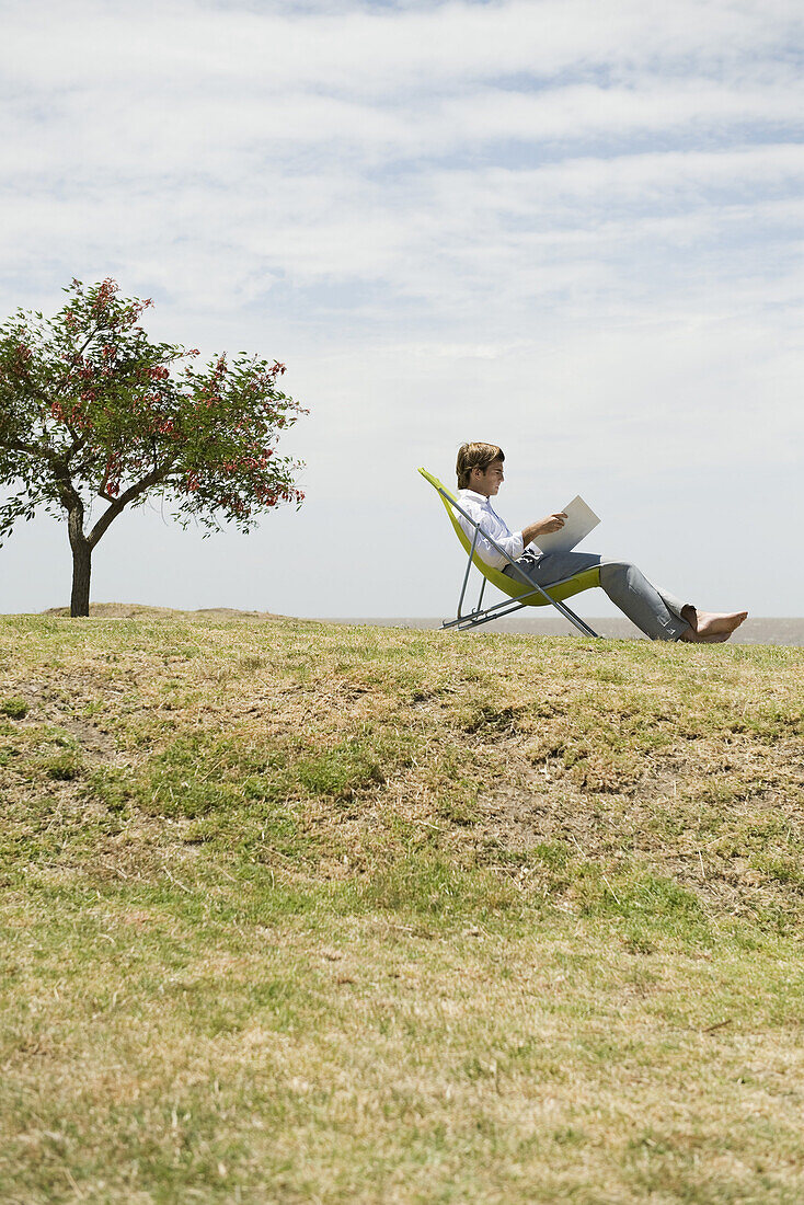 Man relaxing outdoors reading through binder