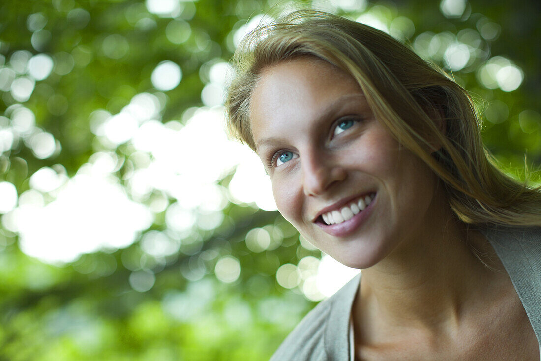 Young woman smiling, looking up, portrait