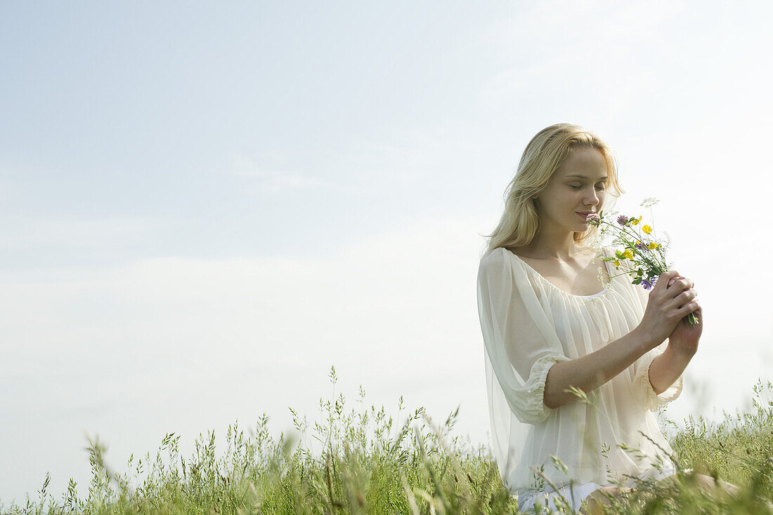 Young woman smelling bouquet of wildflowers