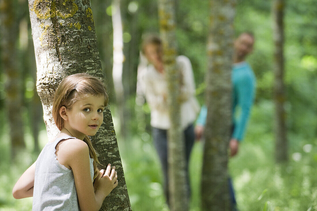 Girl hiding behind tree