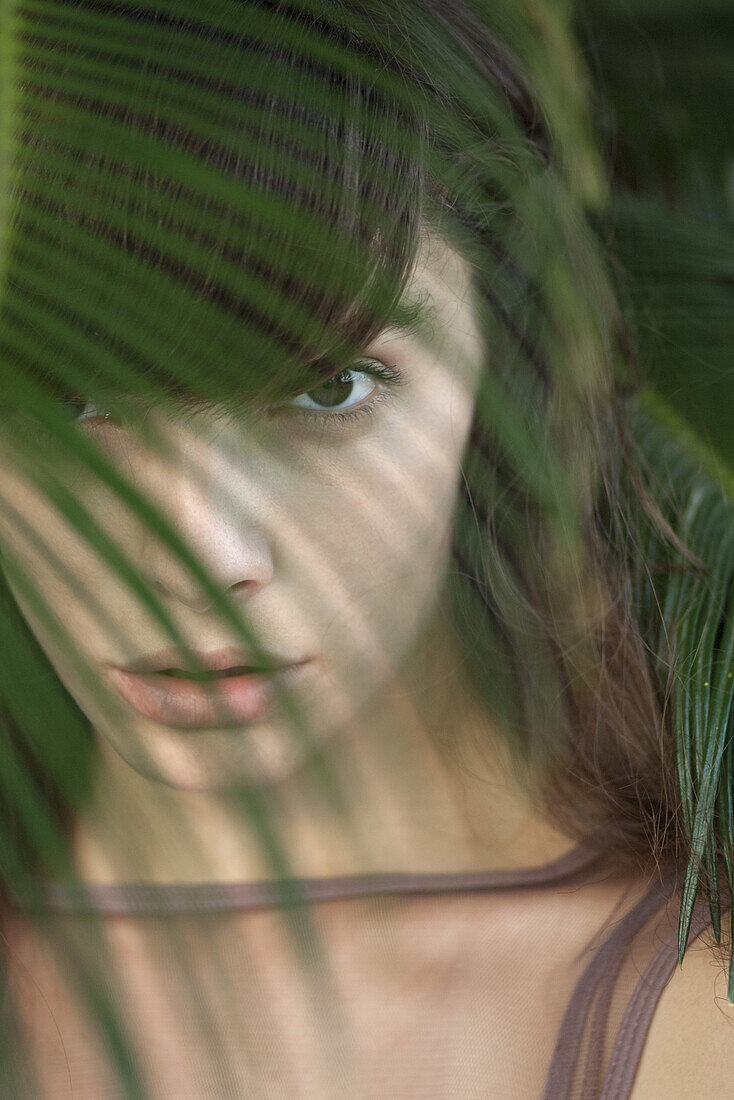Junge Frau hinter Palmenwedel, Porträt
