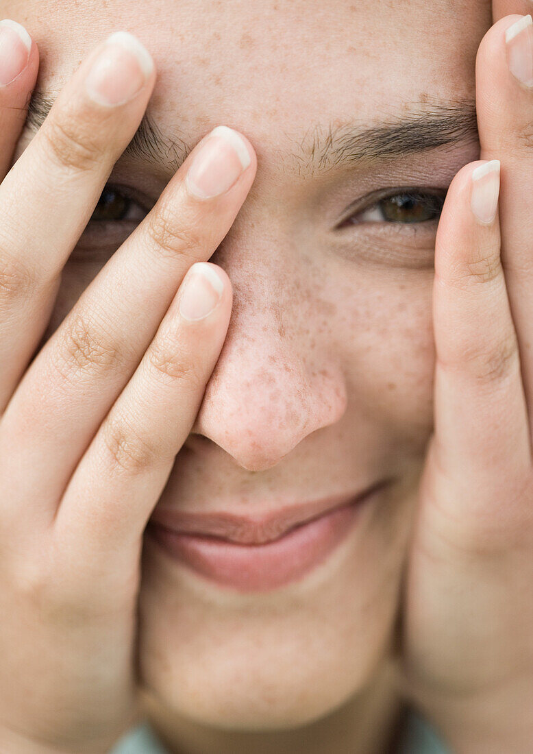 Woman looking through fingers, extreme close-up