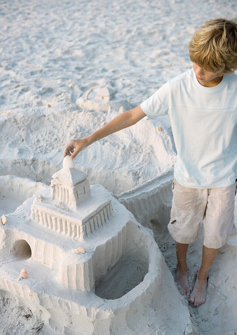 Boy putting finishing touches on sand castle