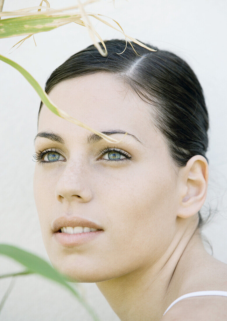 Woman's face, blades of grass in foreground