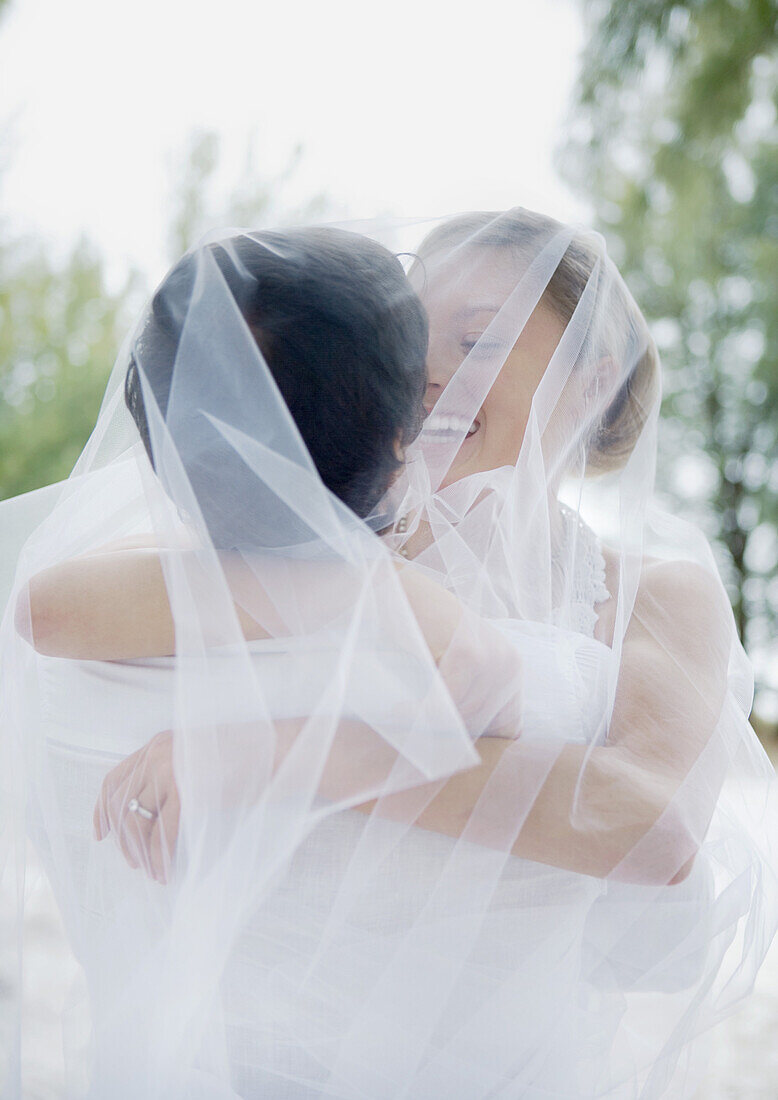 Bride and groom embracing under veil