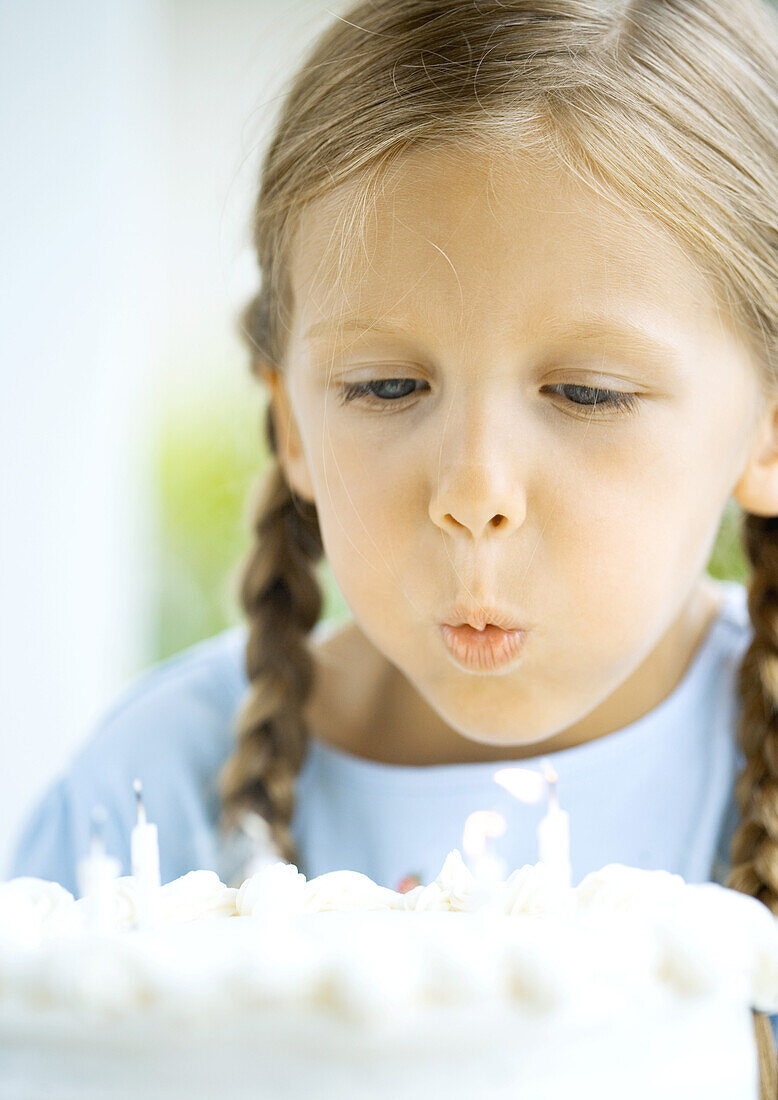 Little girl blowing out candles on birthday cake