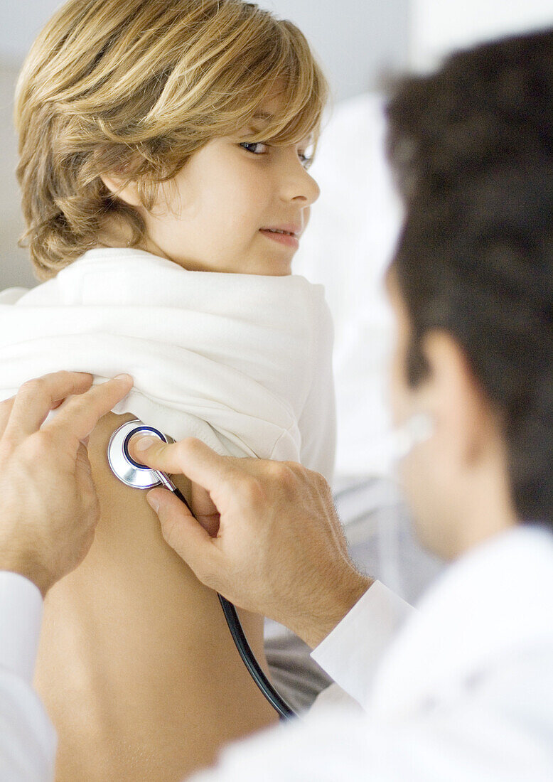 Doctor holding stethoscope to boy's back