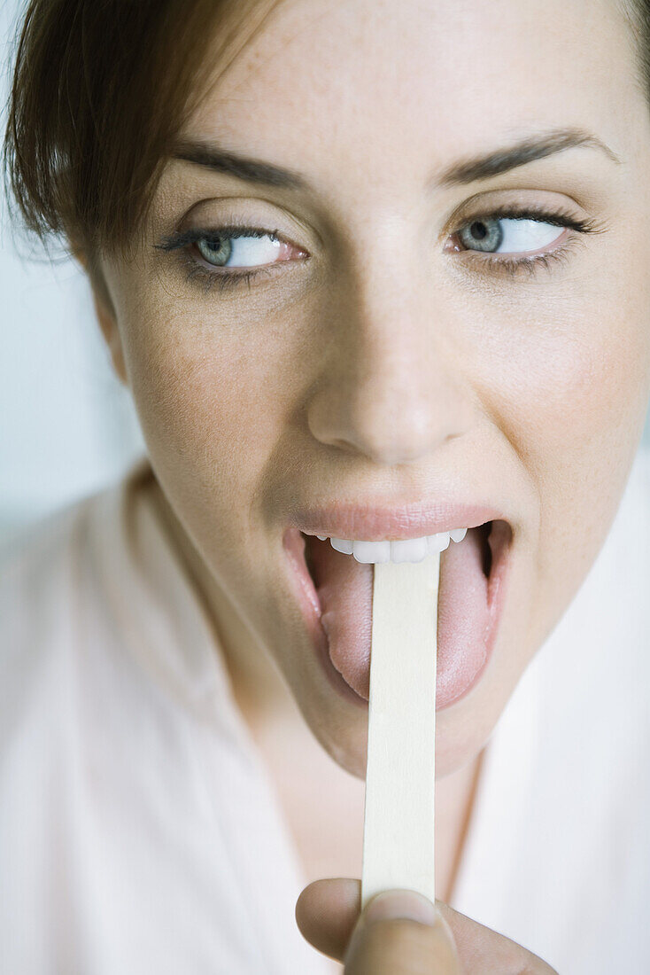 Woman having tongue held down with tongue depressor