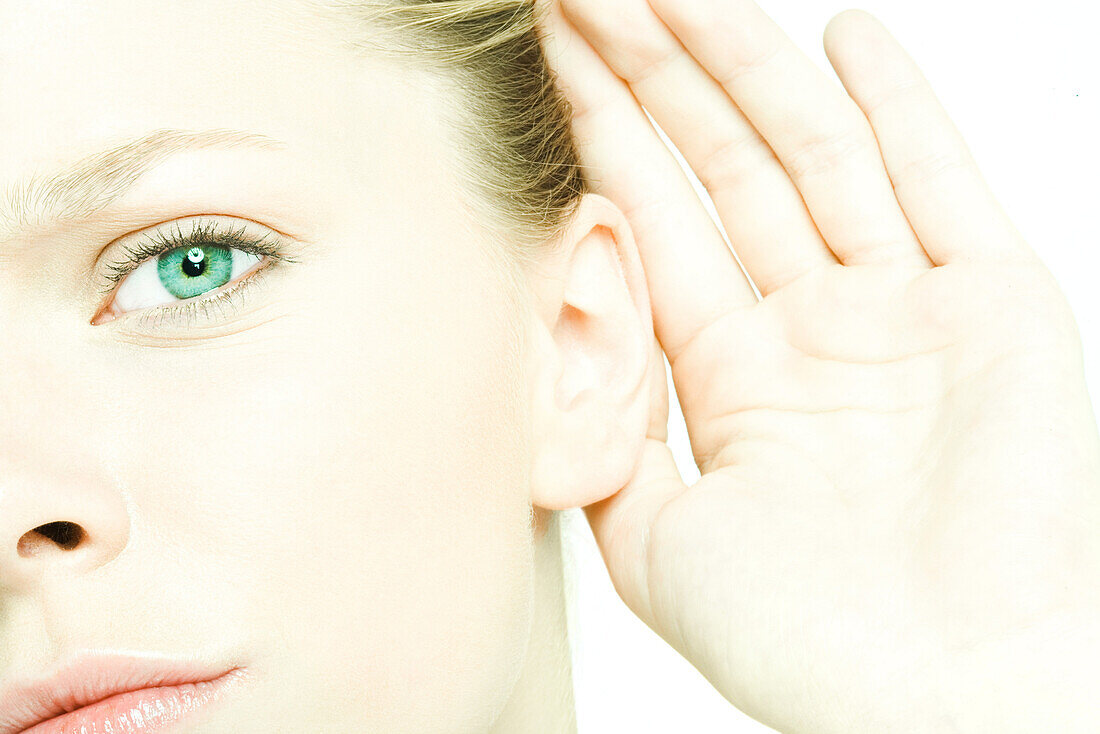 Teenage girl holding hand behind ear, looking at camera, close-up