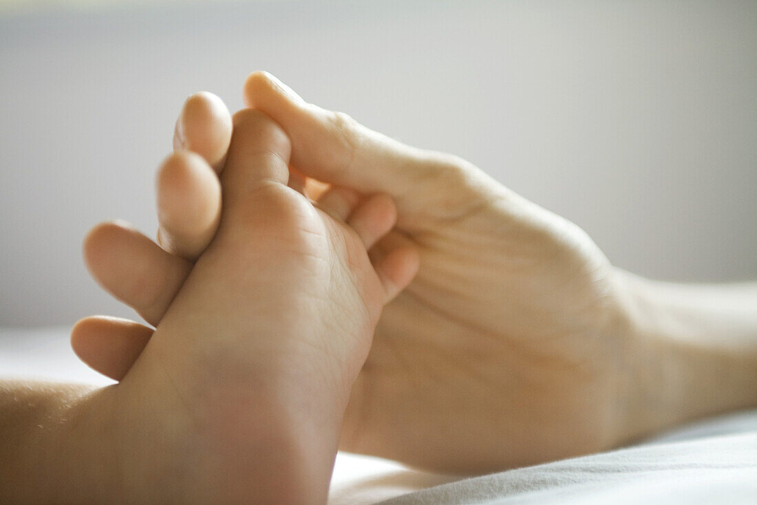 Mother's hand holding baby's foot, close-up