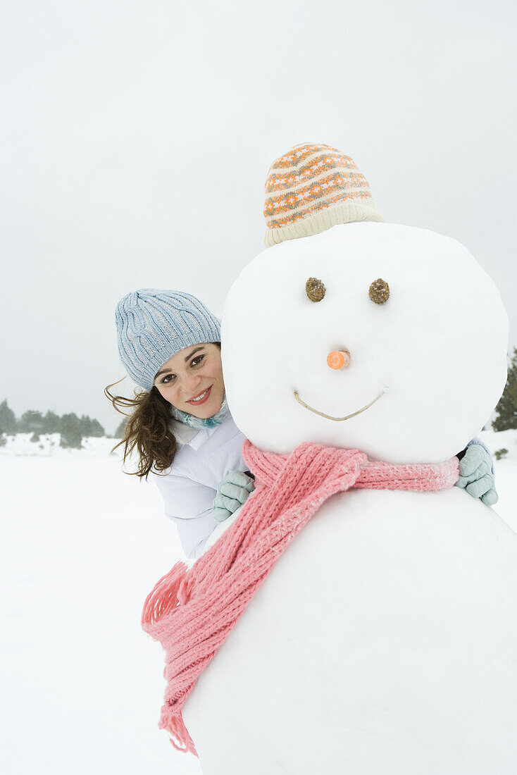 Female embracing snowman, smiling at camera, portrait