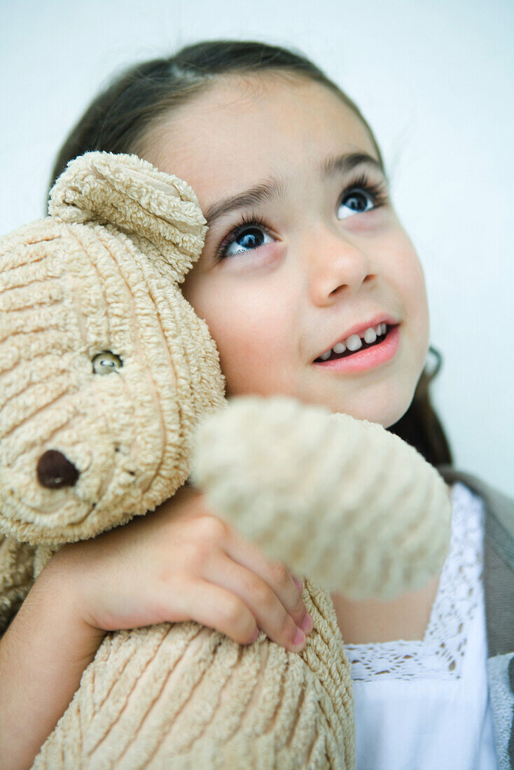 Little girl holding teddy bear, looking up, portrait