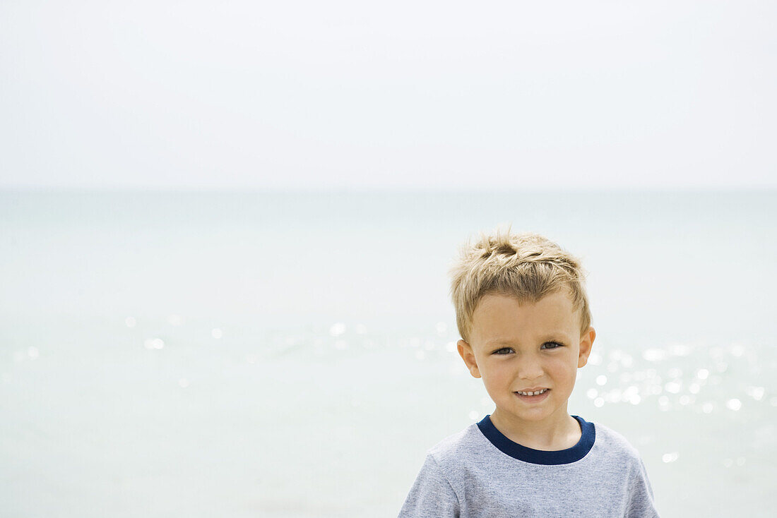 Young boy at the beach, smiling at camera, portrait