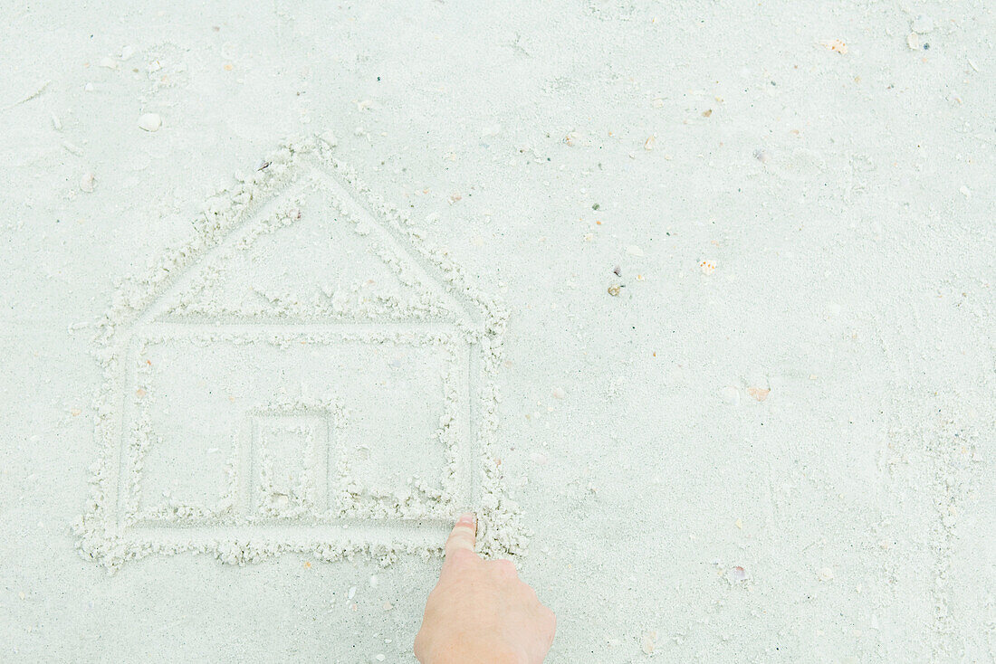 Hand drawing house in sand, cropped view