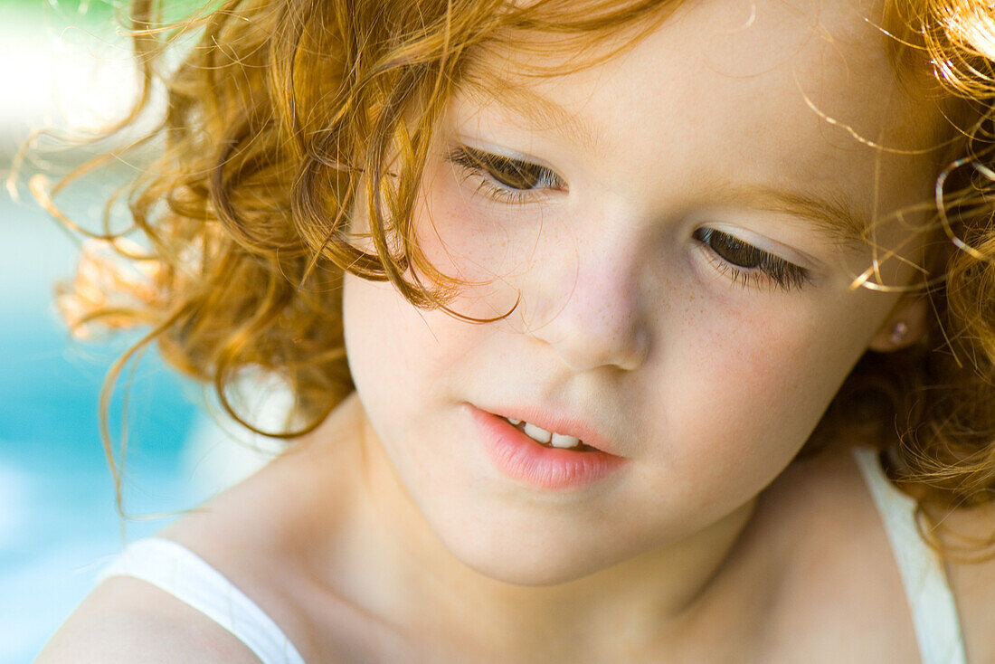 Little girl with red hair looking down, portrait