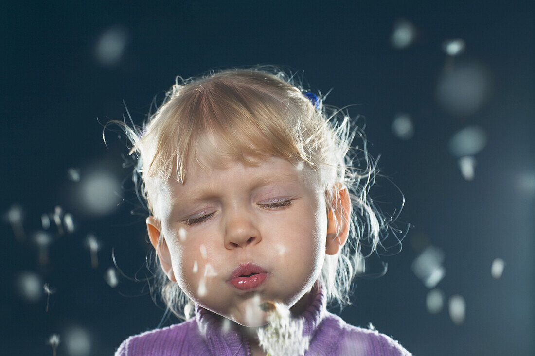 A girl blowing on a dandelion