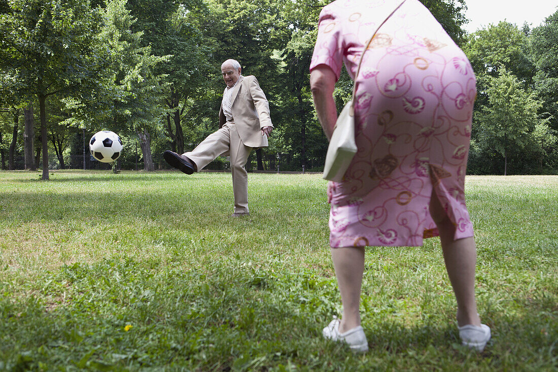 Senior couple play football in the park