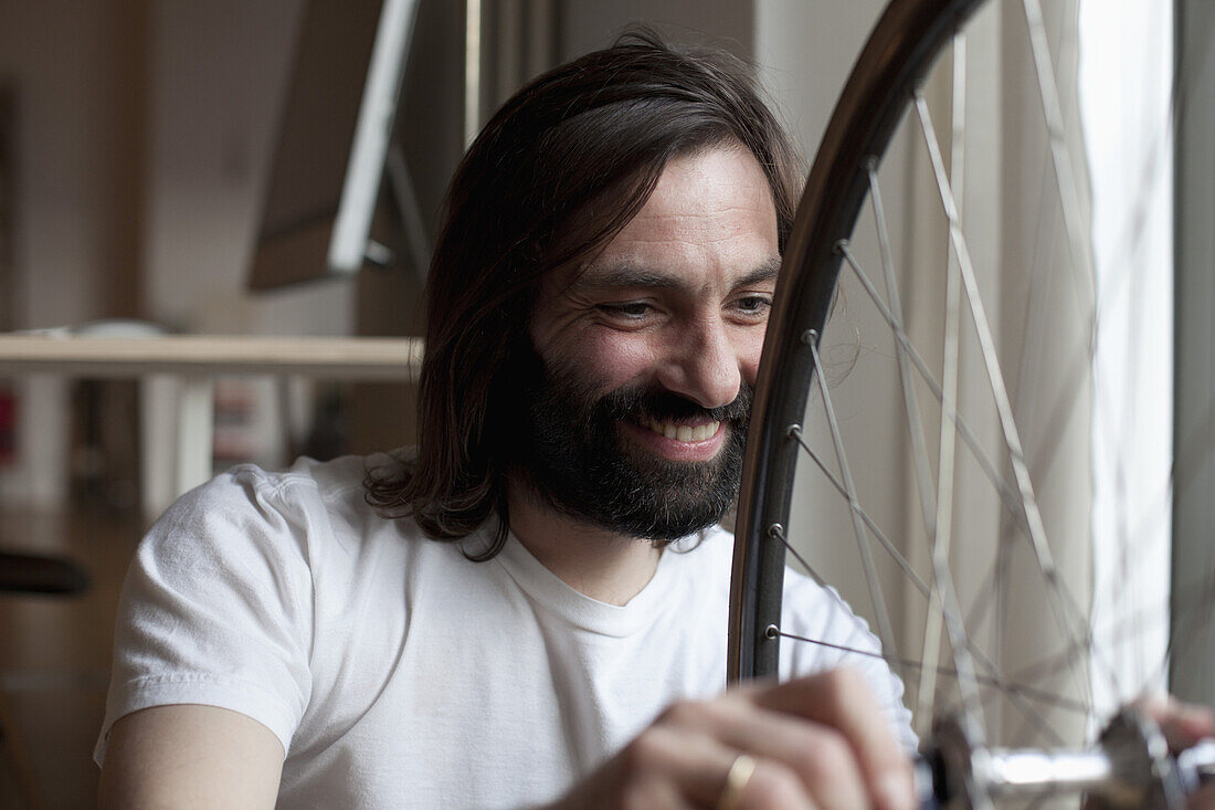 Smiling mid adult man repairing bicycle at home