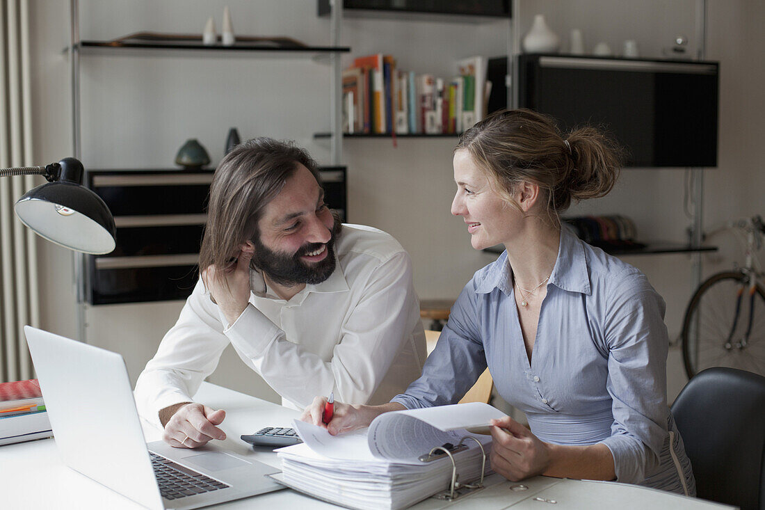Mid adult couple looking at each other while working at home