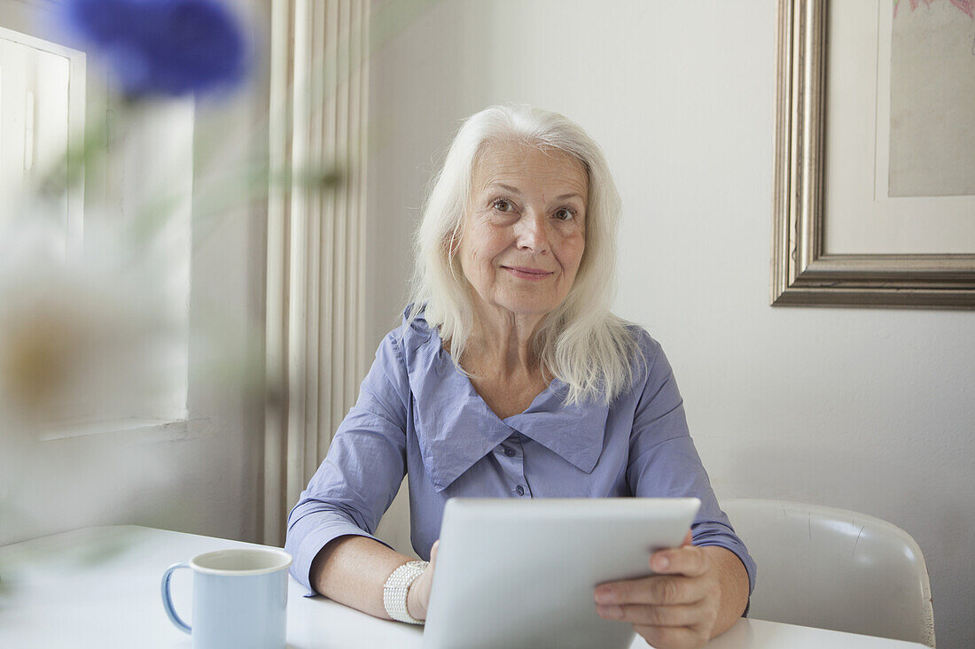 Portrait of confident senior woman holding digital tablet at tablet